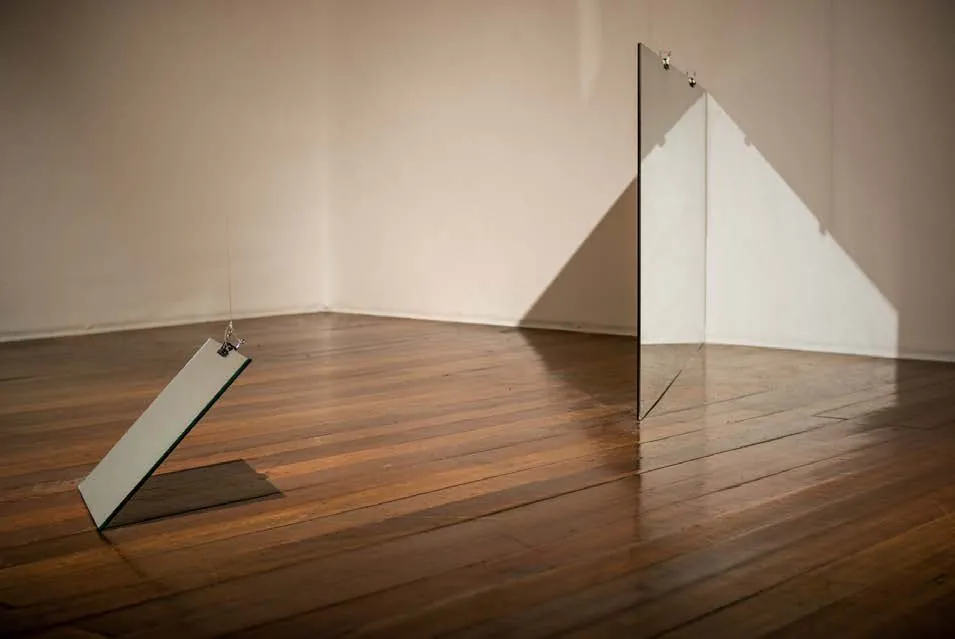 A mirror leaning on the floor beside a standing mirror, casting a triangle of light