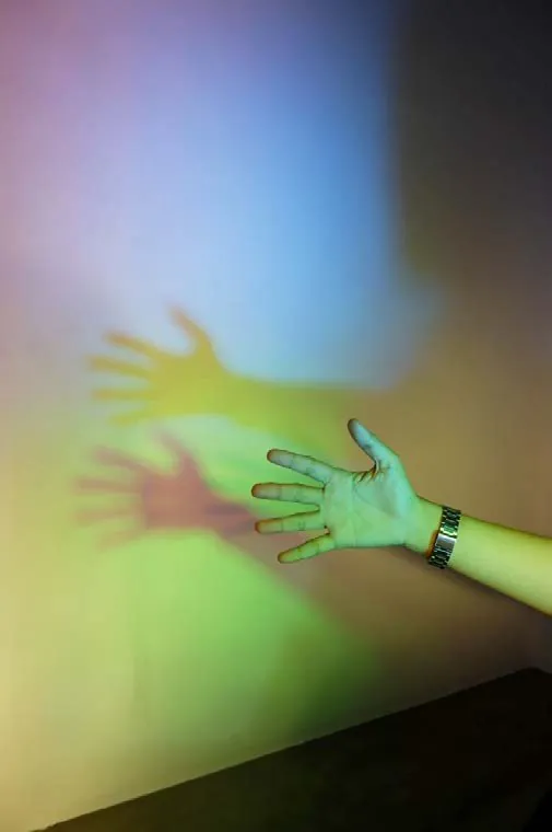 A visitor's hand in the coloured light on the gallery wall