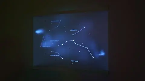 Glowing constellation lines and labels projected onto suspended acrylic glass in a dark room