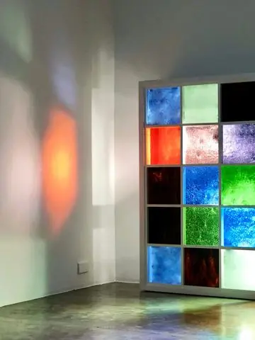 A wall of coloured stained glass panels lit from within, casting orange light