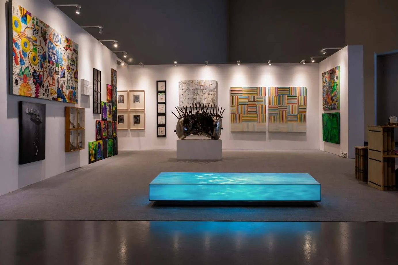 A long lightbox of blue water glowing on the floor of an art fair booth